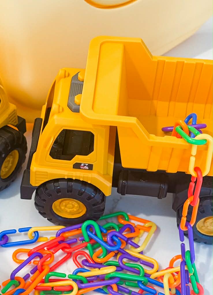 Yellow toy dump truck with colorful chain links on a light background