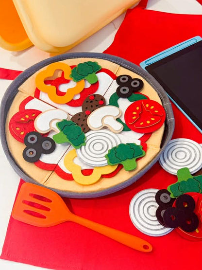 Toy pizza set with felt toppings sitting on a red apron