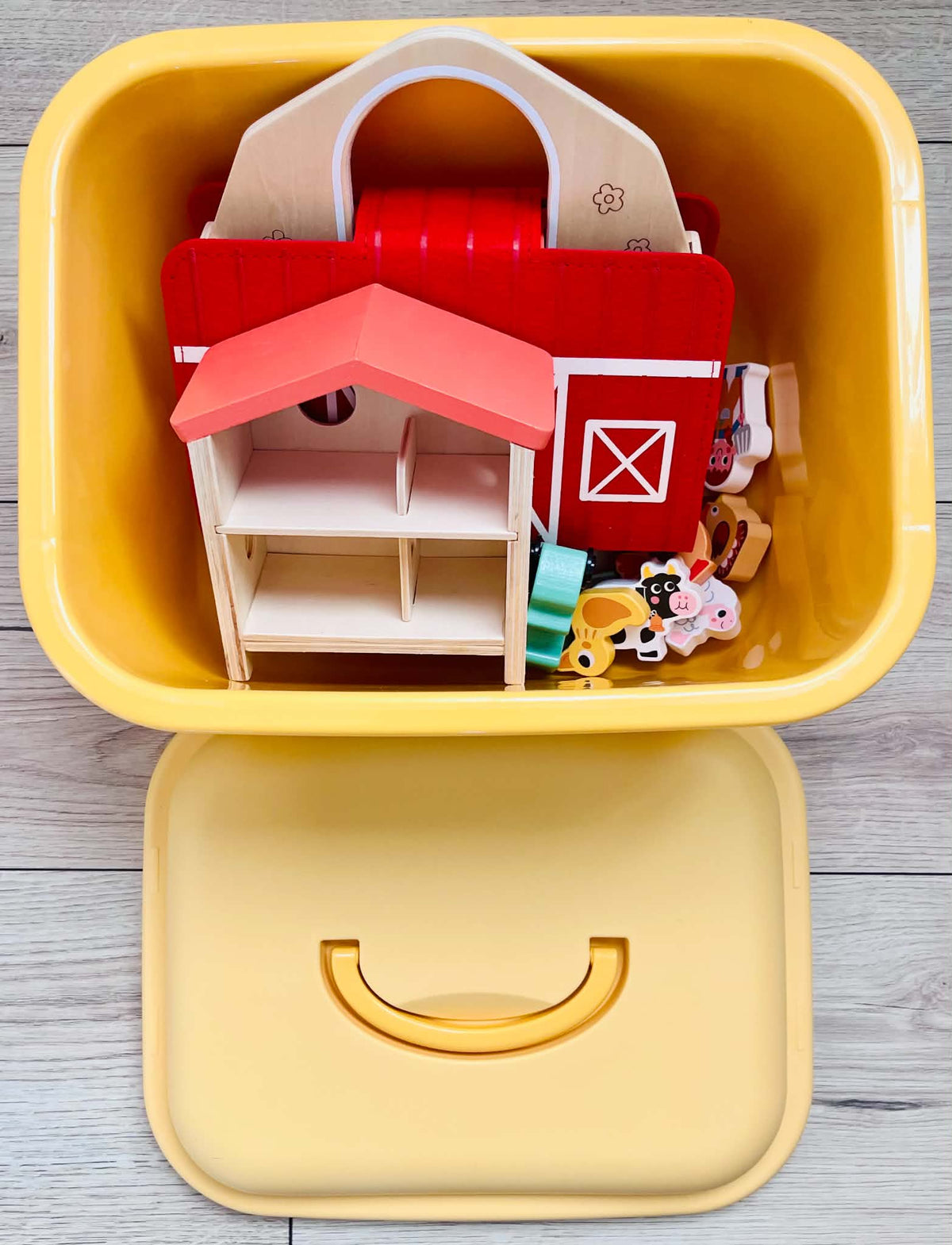 A yellow bin with wooden farm toys inside.