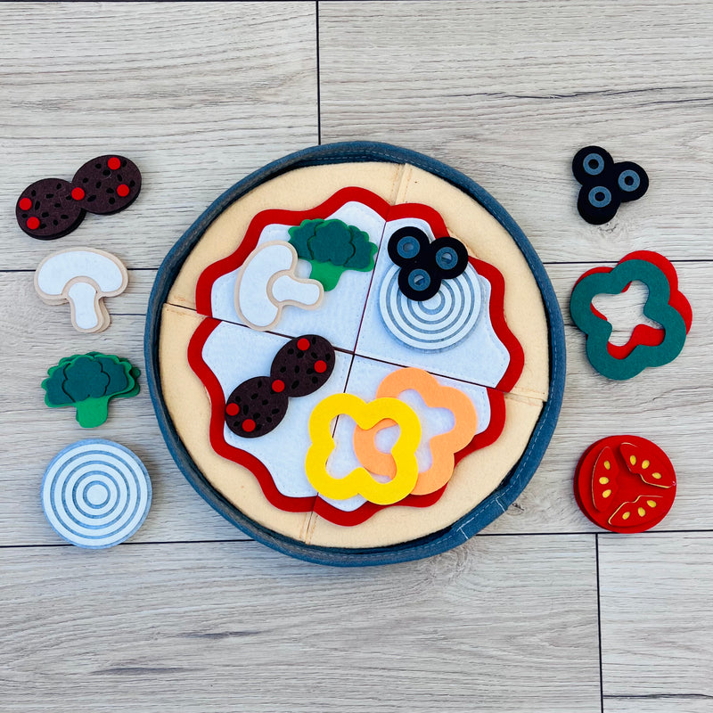 Toy pizza with felt pieces on a wooden surface