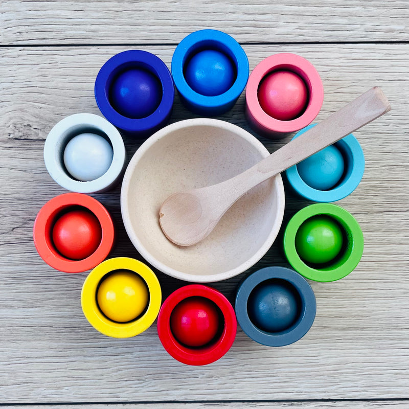 Colorful toy set with a bowl and wooden spoon on a wooden surface